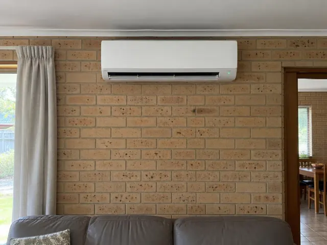 Indoor split system on a brick wall in a carpeted living room in Elizabeth North