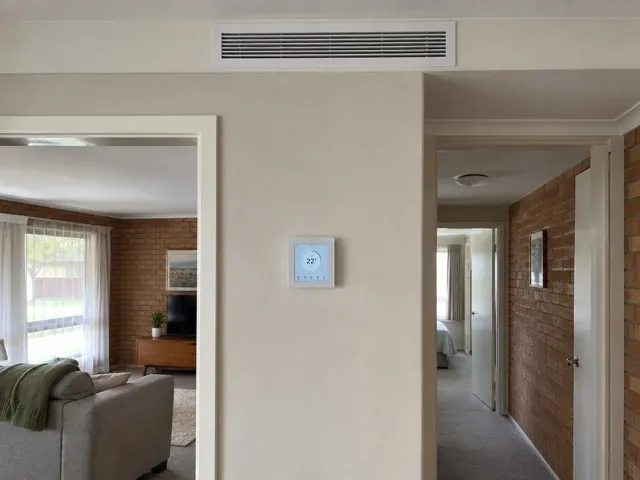 Ceiling return grille and wall controller in a brick interior hallway in Elizabeth Downs